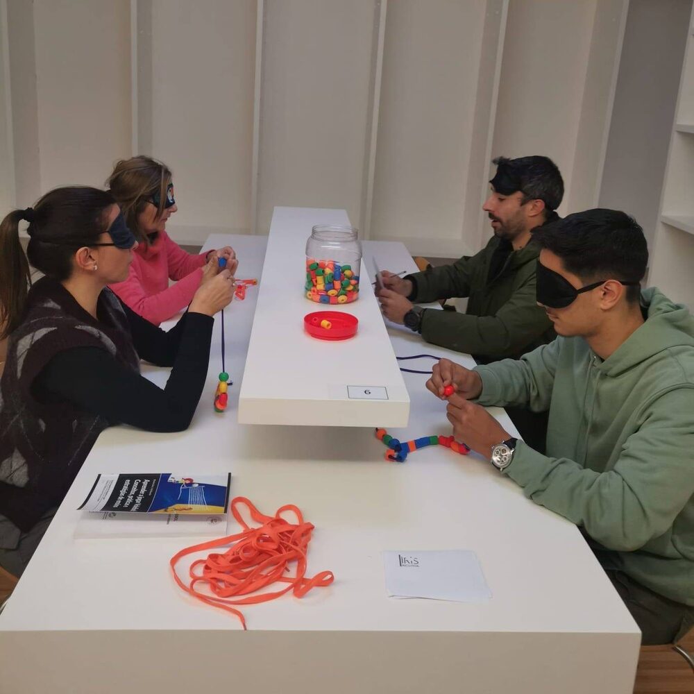 Várias pessoas vendadas realizam uma tarefa de enfiamento